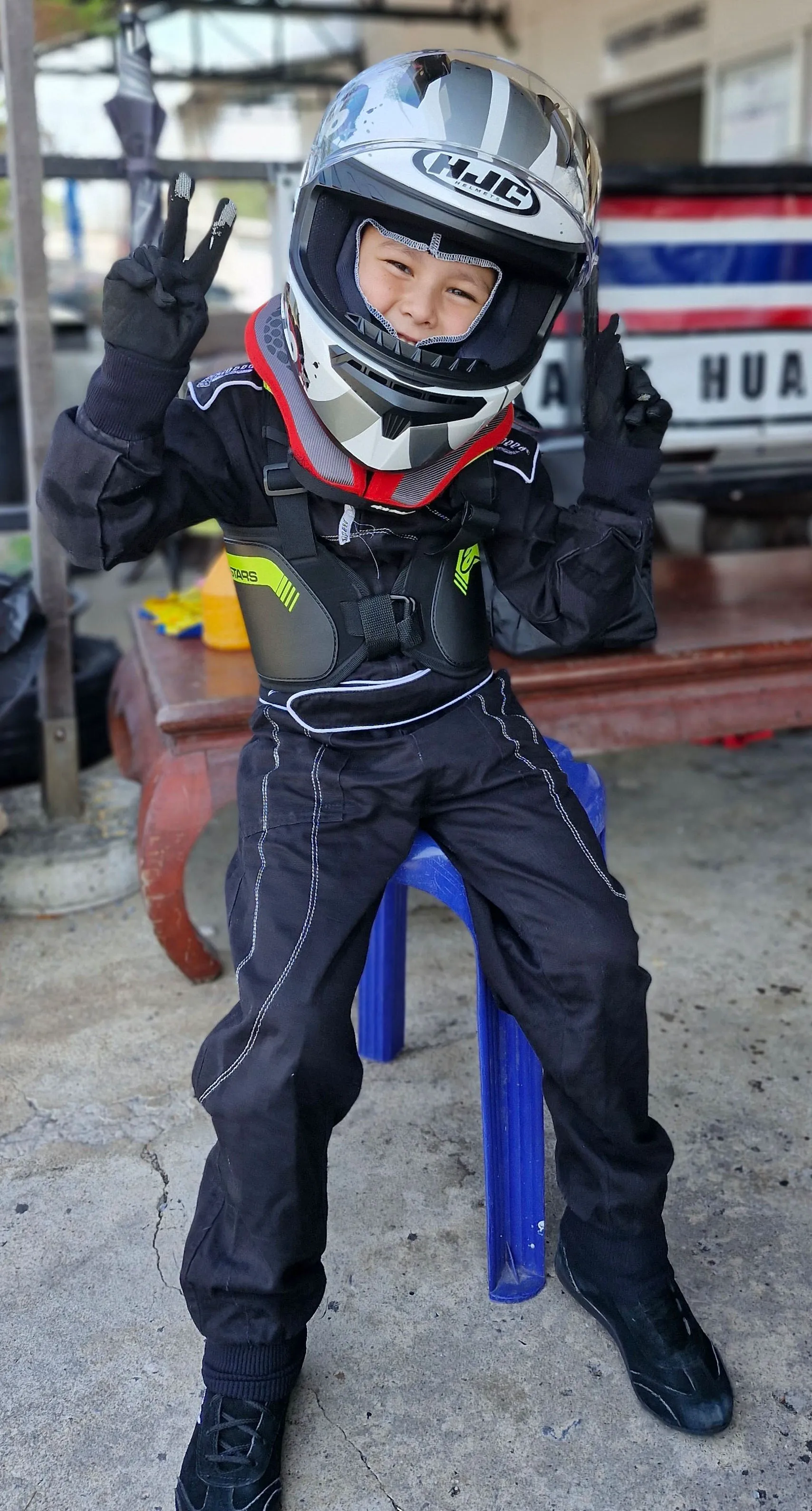 Enea, a 5-year-old kart racing driver from Hua Hin, smiling confidently in his racing suit.
